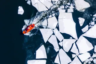 A ship is going through large blocks of ice floating on the sea shot from above