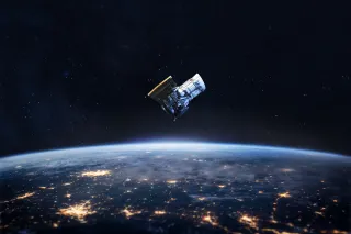 A satellite orbiting in space with earth showing in the background.