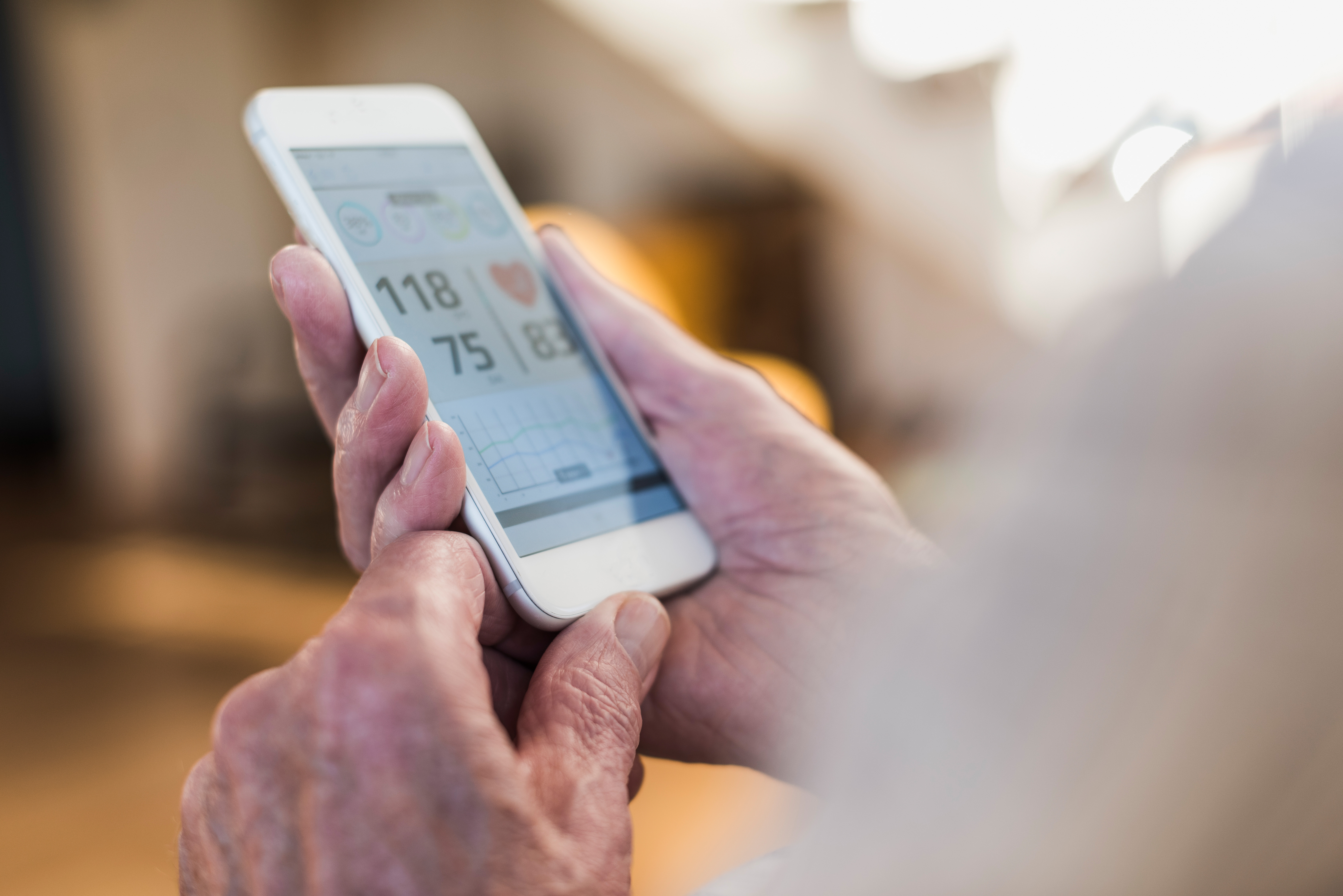 A senior person is holding a smart phone that has a health monitoring app open