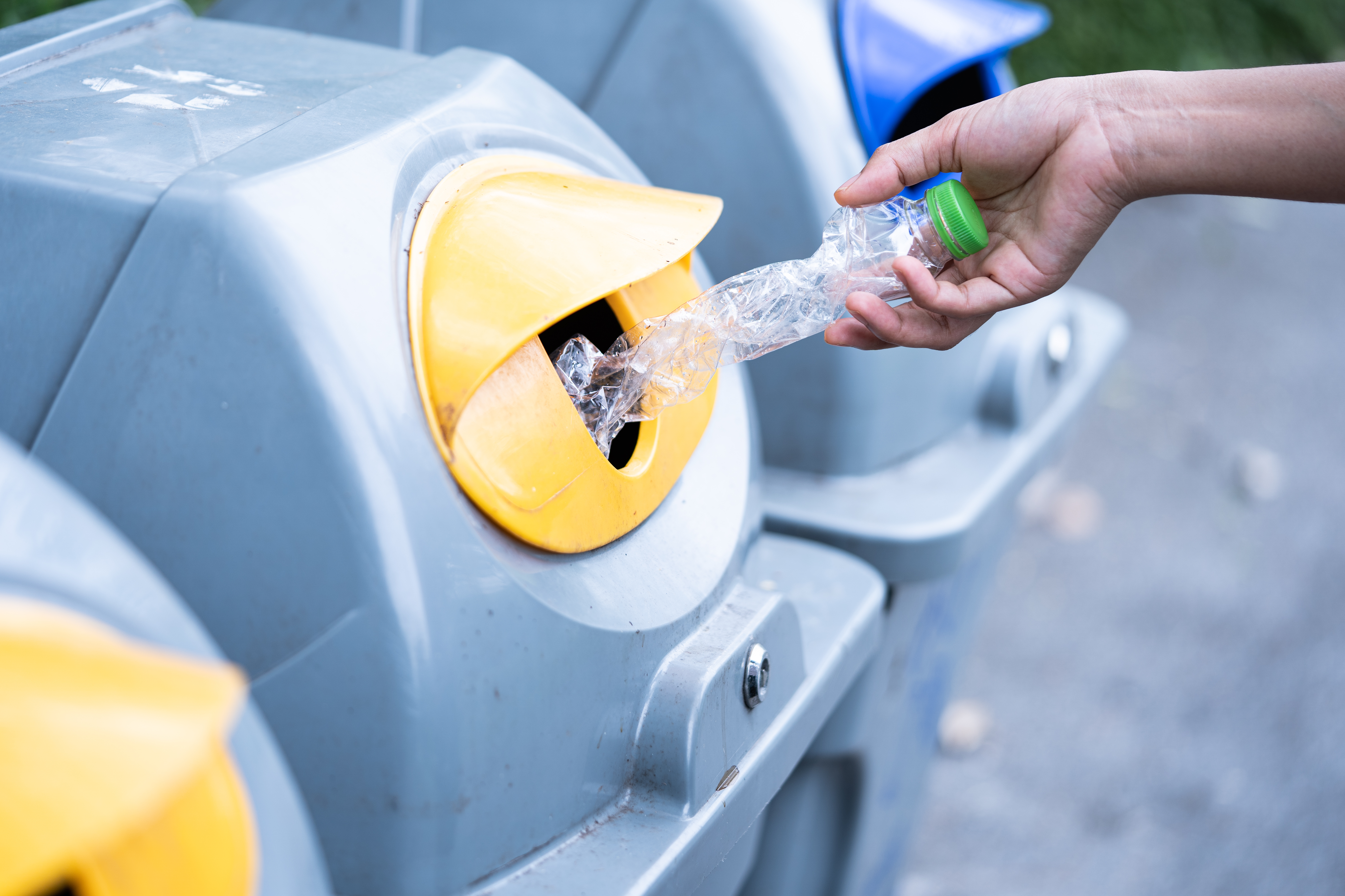 Hand inserting plastic bottle into recycling bin