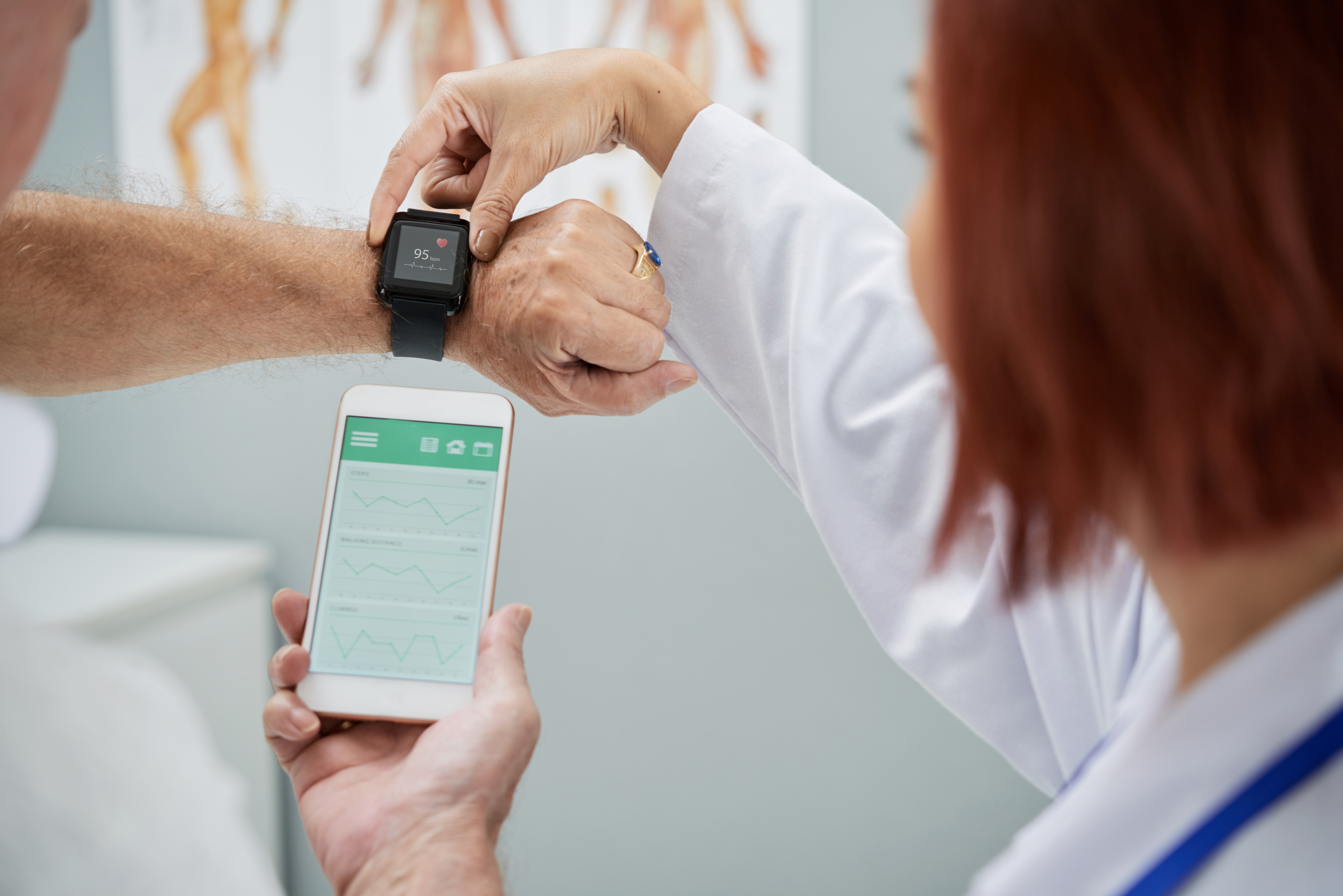 A patient and doctor are examining the readouts from a smartwatch and a smartphone.