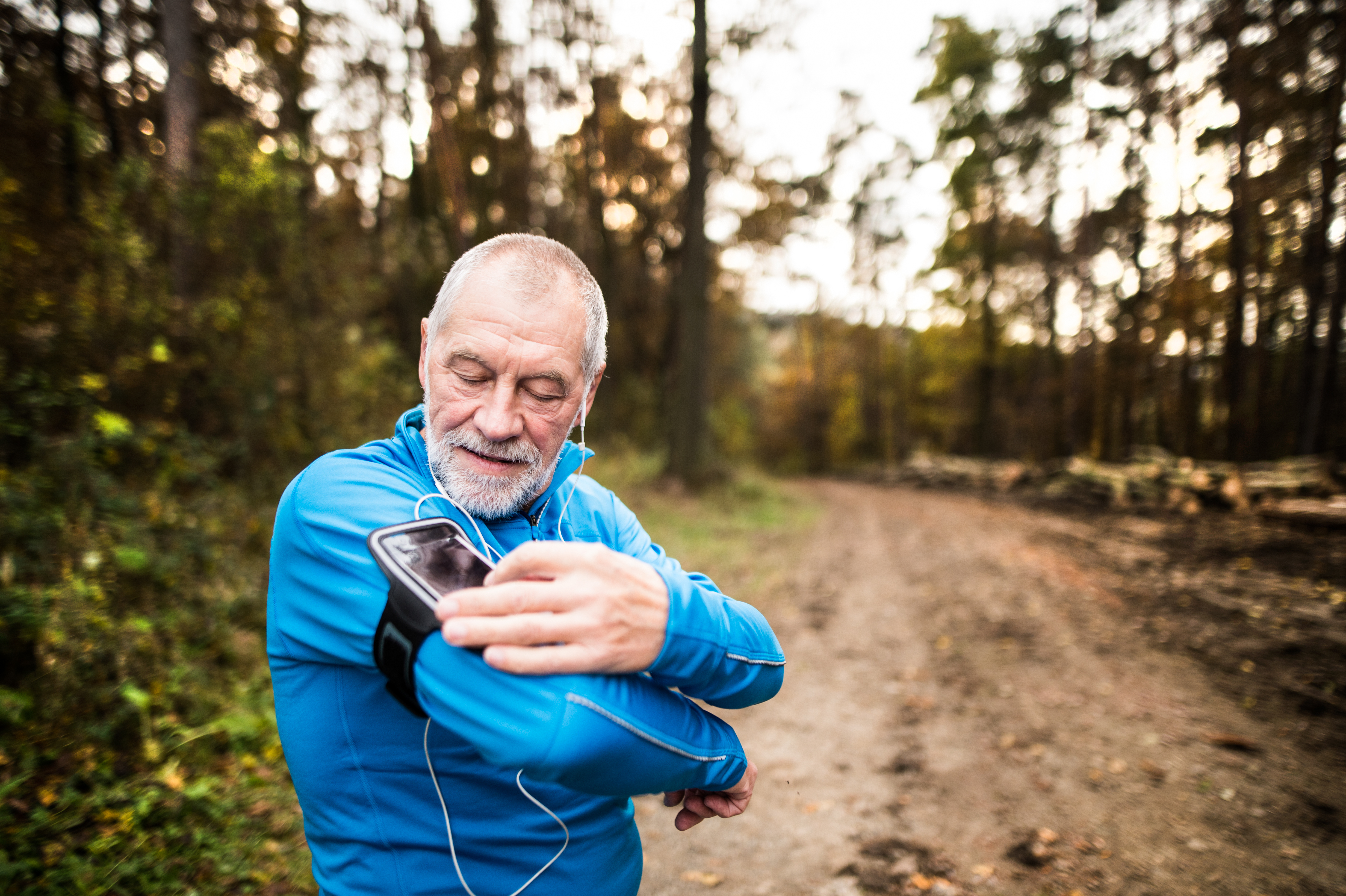 A photo of a jobber is adjusting the volume of his smartphone, which he is listening to with earbuds.