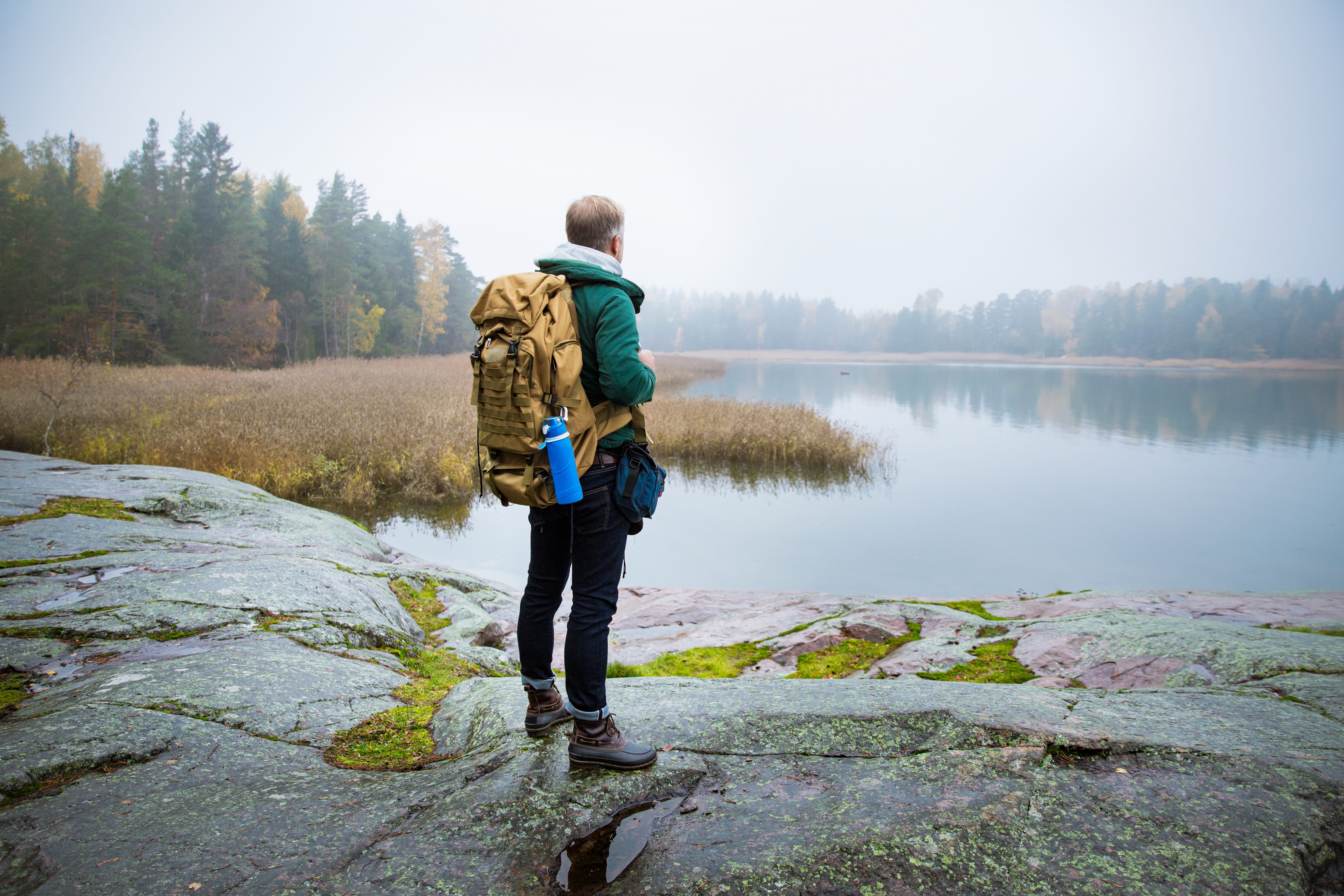 Photo of a man looking out over a lake in a Finnish forest