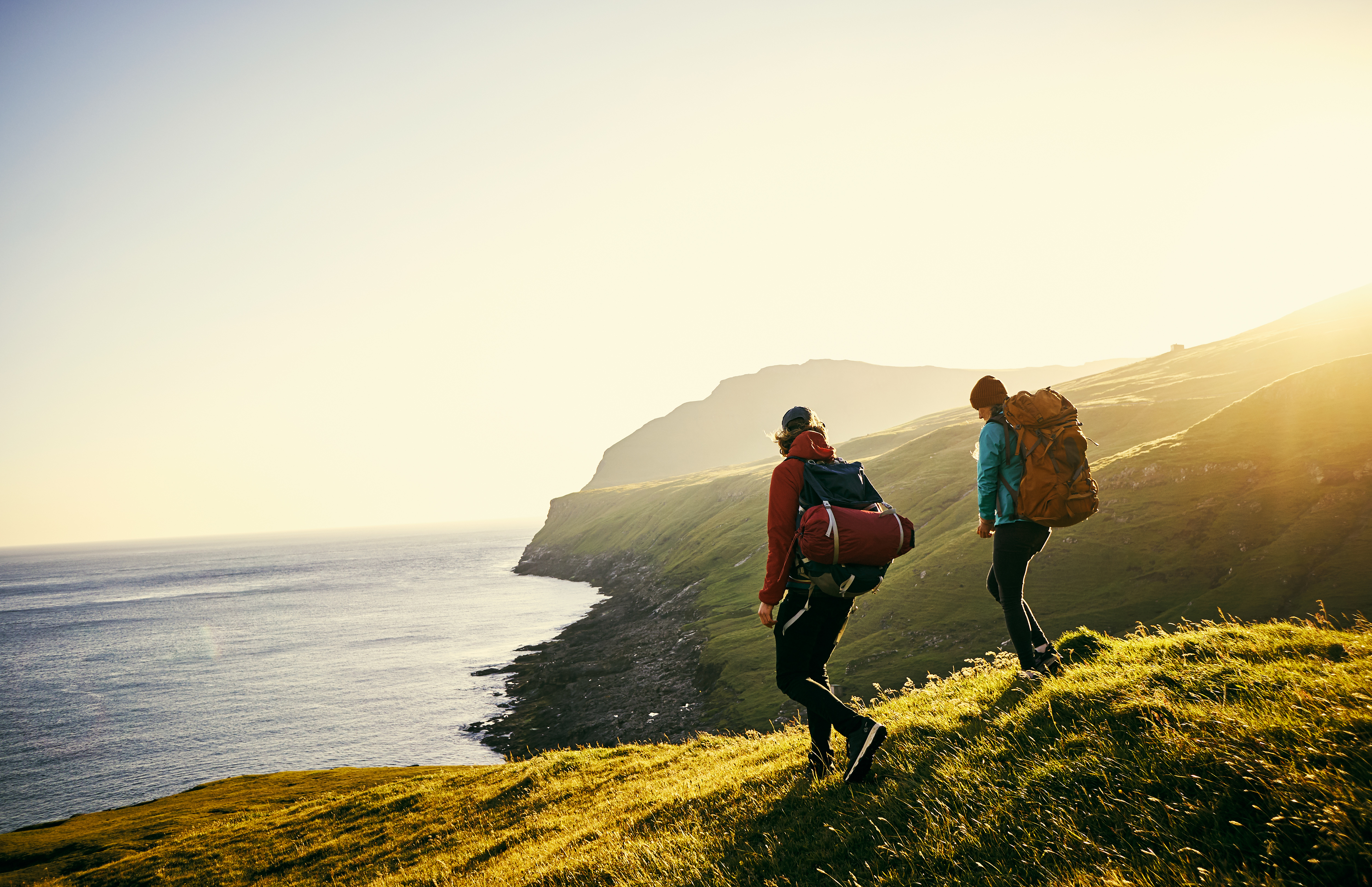 Photo of two people walking on a hill looking over a coastline