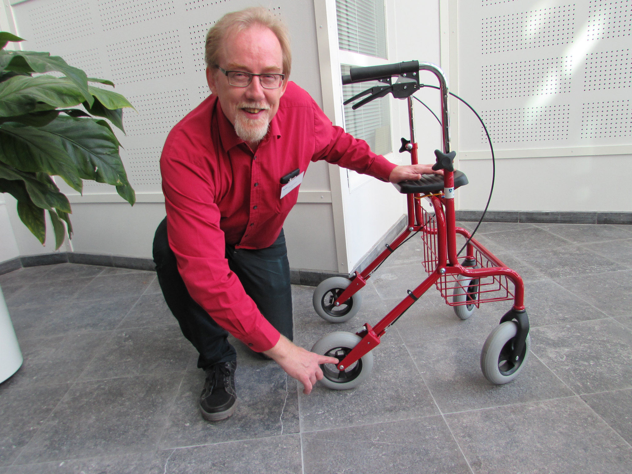 Valokuva Olli Kuusistosta poseeraamassa älyrollaattorin vieressä