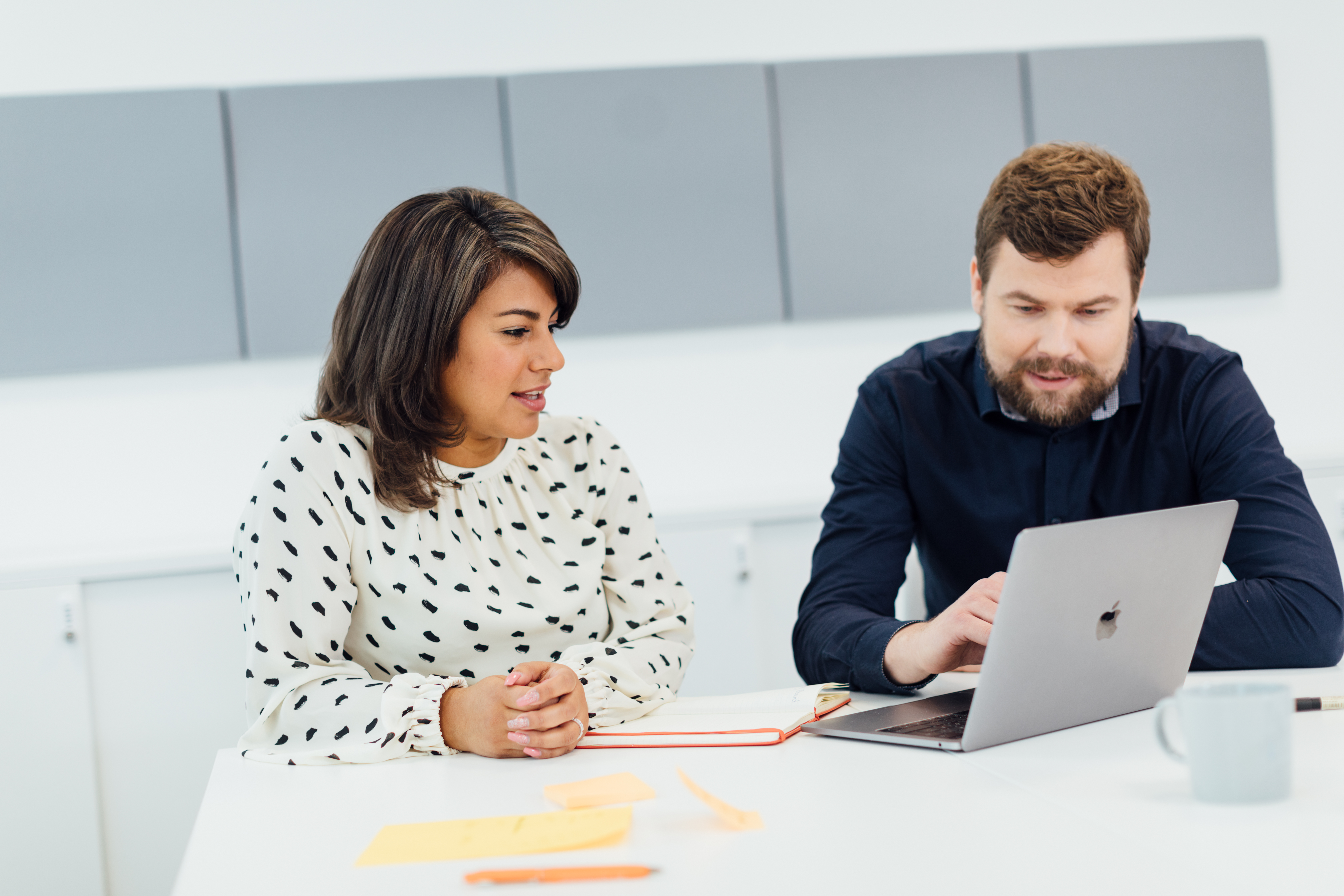 A woman and a man are looking at a laptop screen together
