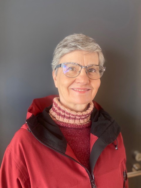 Minna Nissilä smiling at the camera, wearing a red coat.