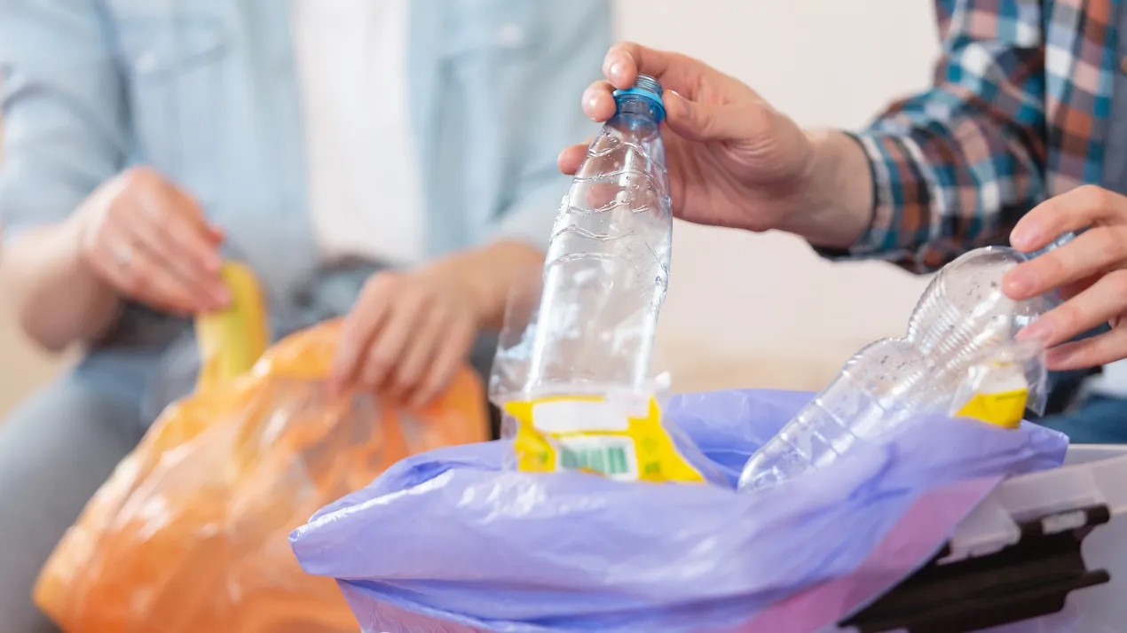 Close up of hands putting plastic bottles in recycling