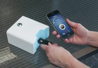 A person is using a device for measuring inflammation value by plugging it into a mobile phone.