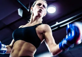 A strong female boxer is throwing a punch