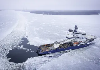 An aerial shot of an icebreaker ship going through ice in arctic conditions
