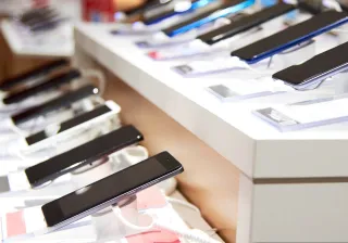 A row of smart phones displayed in a stand in a store