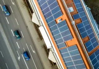 An aerial photo of a building next to a street. The building has solar panels covering the entire roof.