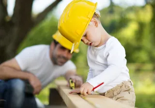 Photo of a child doing woodwork with its father.