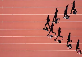 A photo of a group of runners running on a track field.