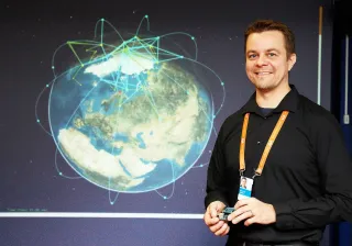 A smiling man , Dr Marko Höyhtyä, standing in front of a space illustration