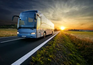 A bus is driving down the road at sunset