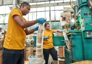 Young african american man workingTwo people throwing used disposable cups into rubbish pressing machine on waste station
