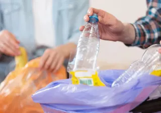 Close up of hands putting plastic bottles in recycling