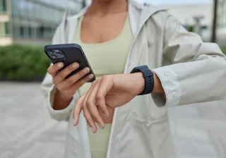 nainen katsoo älypuhelintaan ja kännykkäänsä