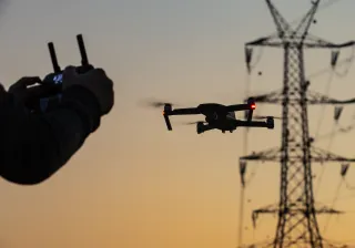 Person flying a drone next to a power tower