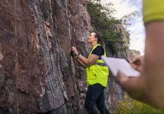 Huomioliiviin pukeutunut henkilö tarkastaa kalliorakenteita
