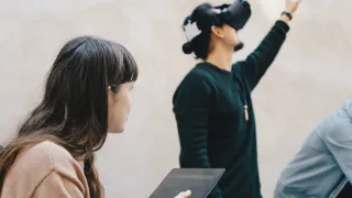 One person is using a tablet and another is using VR glasses