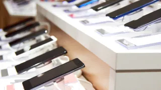 A row of smart phones displayed in a stand in a store