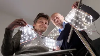 Two persons, ​Flexbright’s CEO Pekka Makkonen and CCO Atte Varsta, are holding a  sheet of flexible, lightweight LED foil