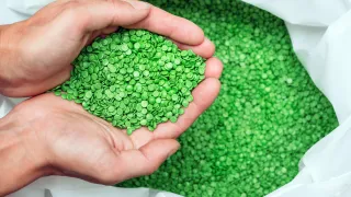 A closeup photo of a pair of hands scooping up recyclable plastic pellets.