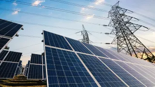 A photo of solar panels with power lines in the background.