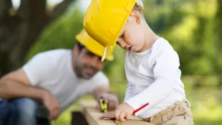 Photo of a child doing woodwork with its father.