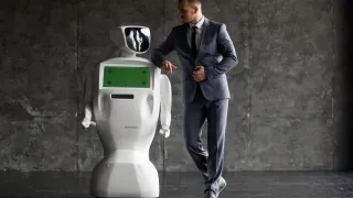 Photo of a man standing next to  humanlike robot