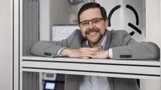 Pekka Pursula smiling at the camera, quantum computer in the background