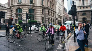 people walking and riding bikes on a busy city street crossing