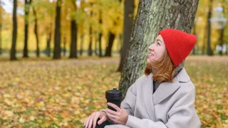 A woman sitting in a forest holding a recyclable cup