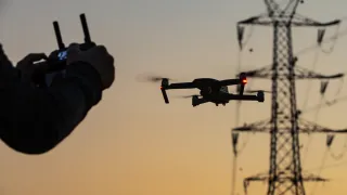 Person flying a drone next to a power tower