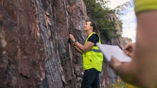 Huomioliiviin pukeutunut henkilö tarkastaa kalliorakenteita
