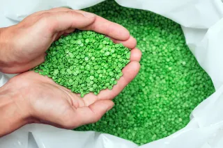 A closeup photo of a pair of hands scooping up recyclable plastic pellets.