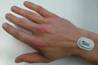 Hand with a small sticker sensor attached to the wrist