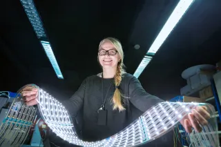 Person holding up long sheet of flexible printed electronics