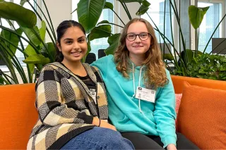 Maia and Sylvi sitting on an orange couch at the VTT office and smiling at the camera