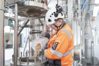 a scientist pouring biomass into a tank