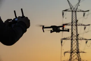 Person flying a drone next to a power tower
