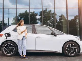 a woman charging an electric car while on her mobile phone