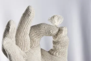 hand wearing a glove and holding some yarn